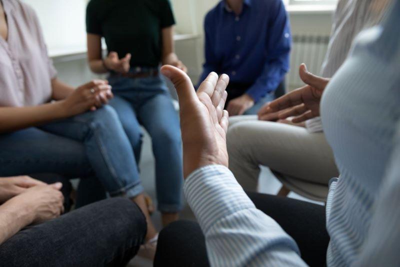Photo of people in meeting circle, with focus on hands communicating